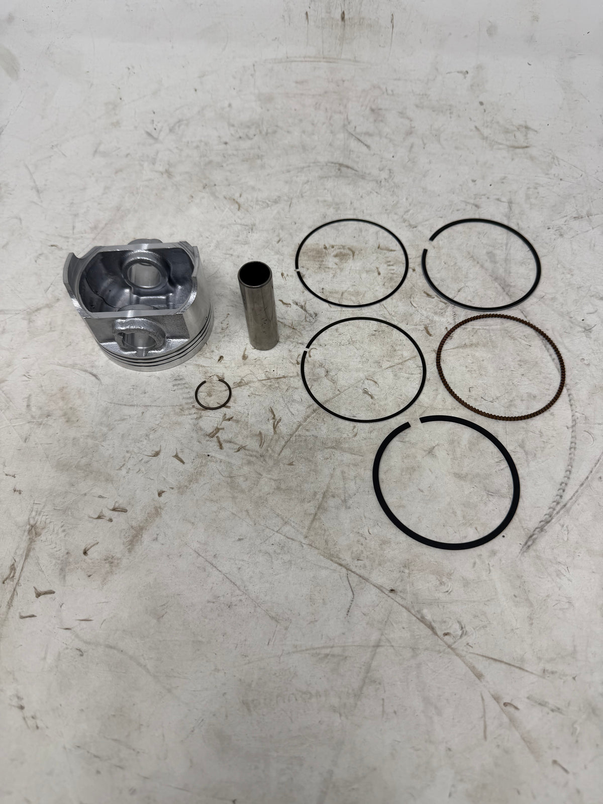 Underside view of the DF250RTG Sportster 250cc piston kit with piston pin, ring set and one retaining clip