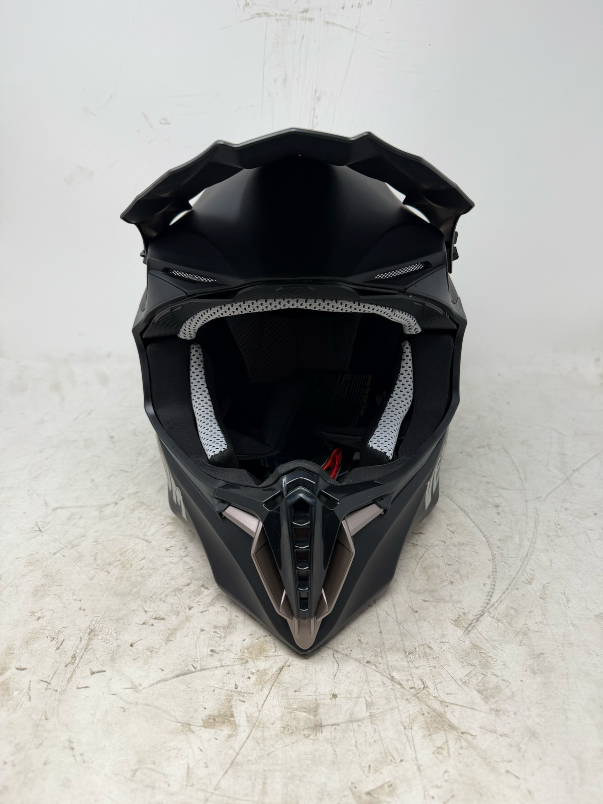 Front view of black motocross helmet with peak visor, open eye port and chin bar